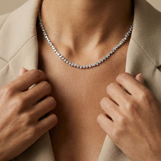 Person wearing a delicate necklace with a neutral background