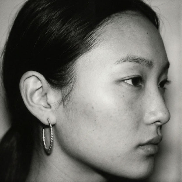 Close-up of a person wearing a gold necklace with a green pendant.