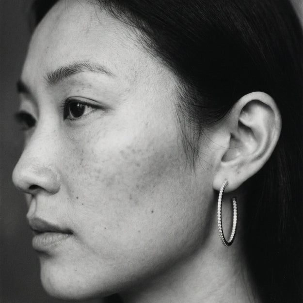 Black and white close-up of a person's ear and side of face with hoop earring.
