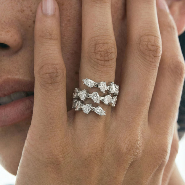 Close-up of a hand wearing three diamond rings on a blurred background