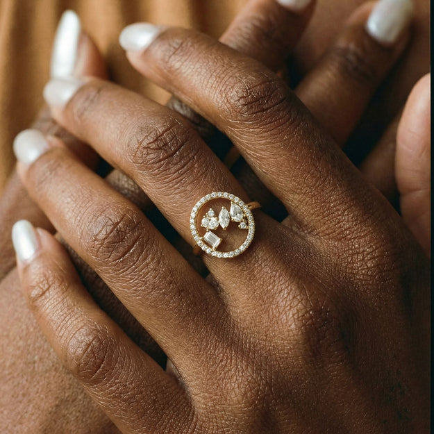 Close-up of a hand wearing a decorative ring with a brown background