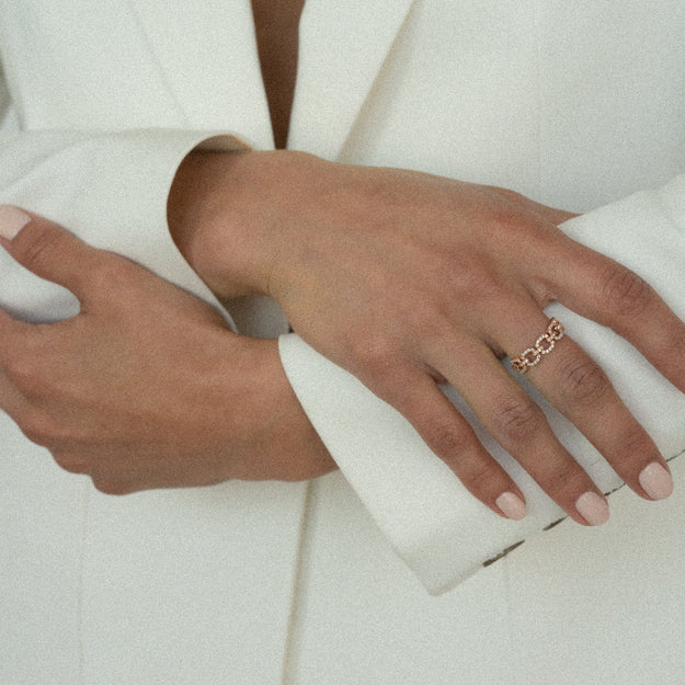 Close-up of hands wearing gold rings on a white background