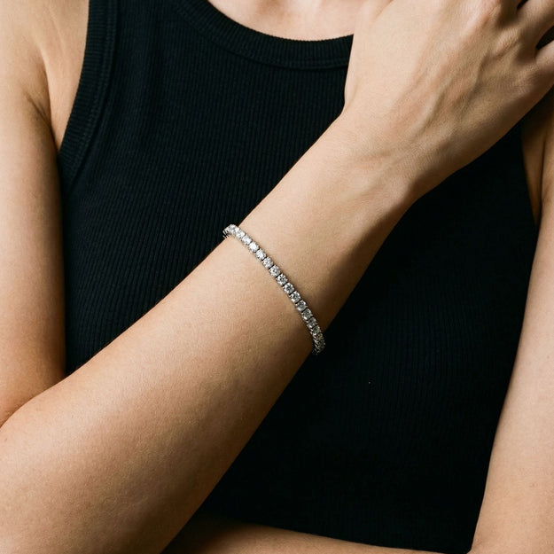 Person wearing a silver bracelet on a black background
