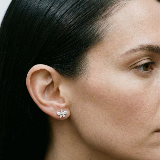 Close-up of a woman wearing a diamond earring with a plain background