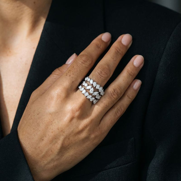 Hand wearing a diamond ring with a dark background
