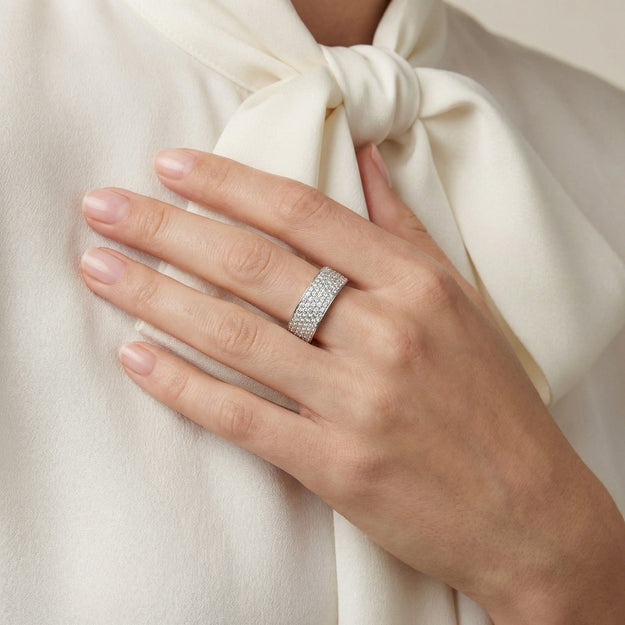 Hand wearing a diamond ring on a white fabric background