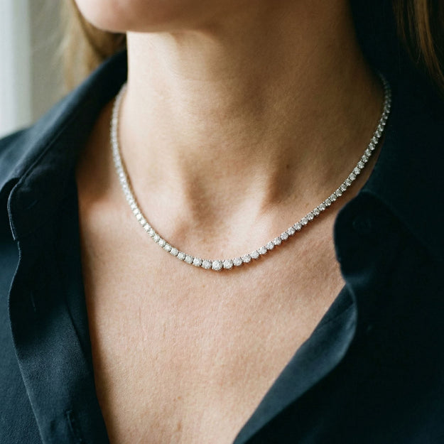 Close-up of a person wearing a diamond necklace with a blurred background