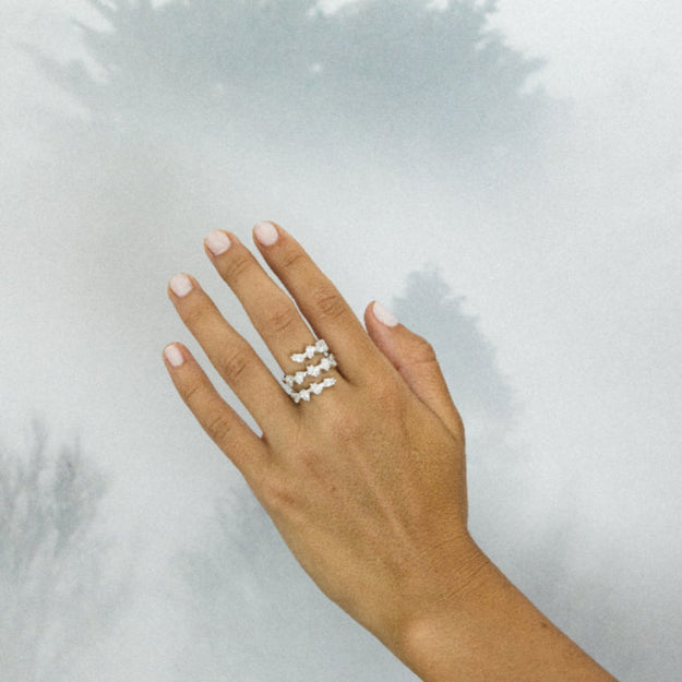 Hand wearing a gold ring on a light gray background
